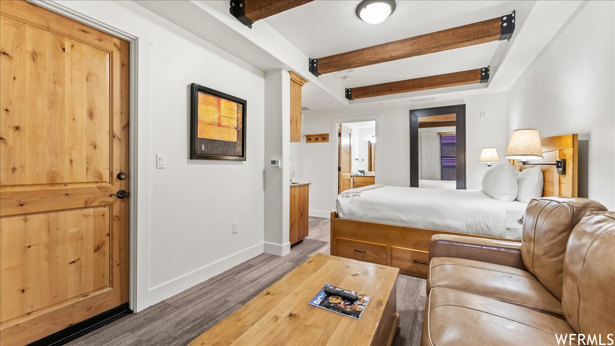 Hardwood floored bedroom featuring beamed ceiling