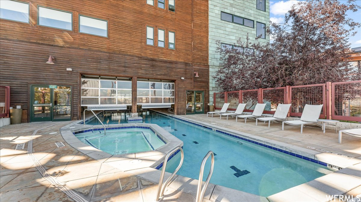 View of pool with a patio area and a hot tub