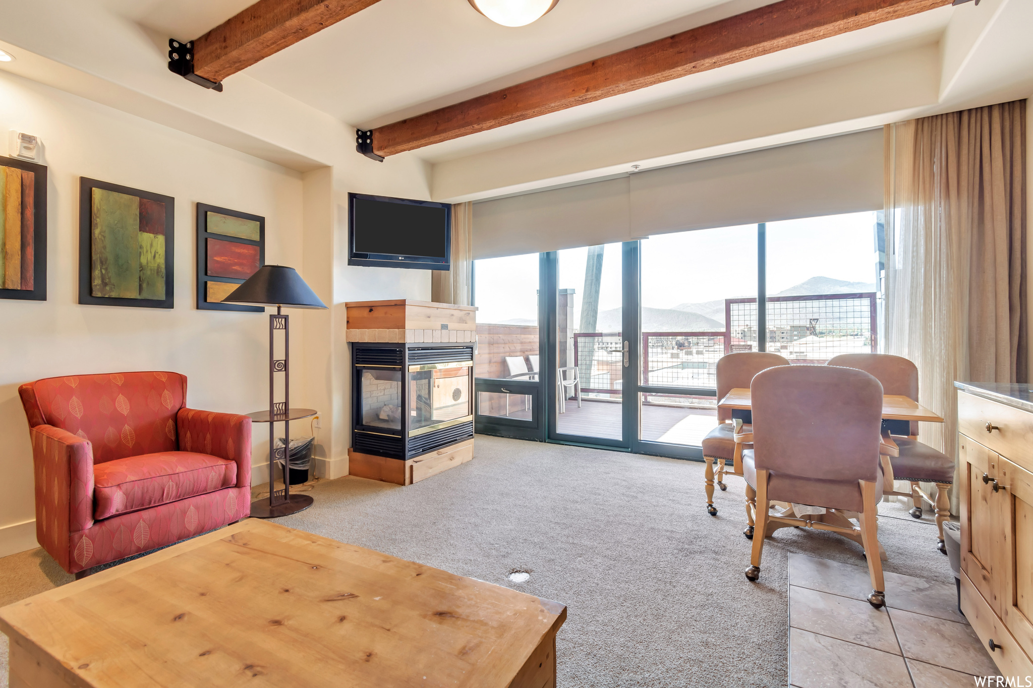 Office with light colored carpet, a fireplace, and beamed ceiling