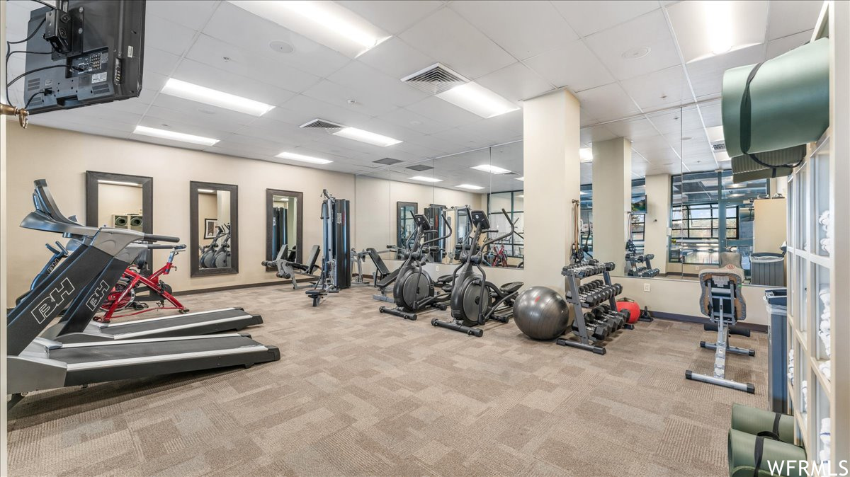 Exercise room with light colored carpet and a drop ceiling