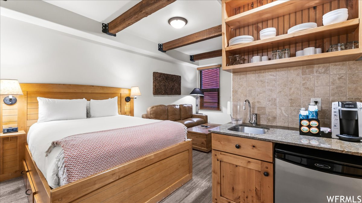 Bedroom featuring sink, light hardwood floors, and beamed ceiling