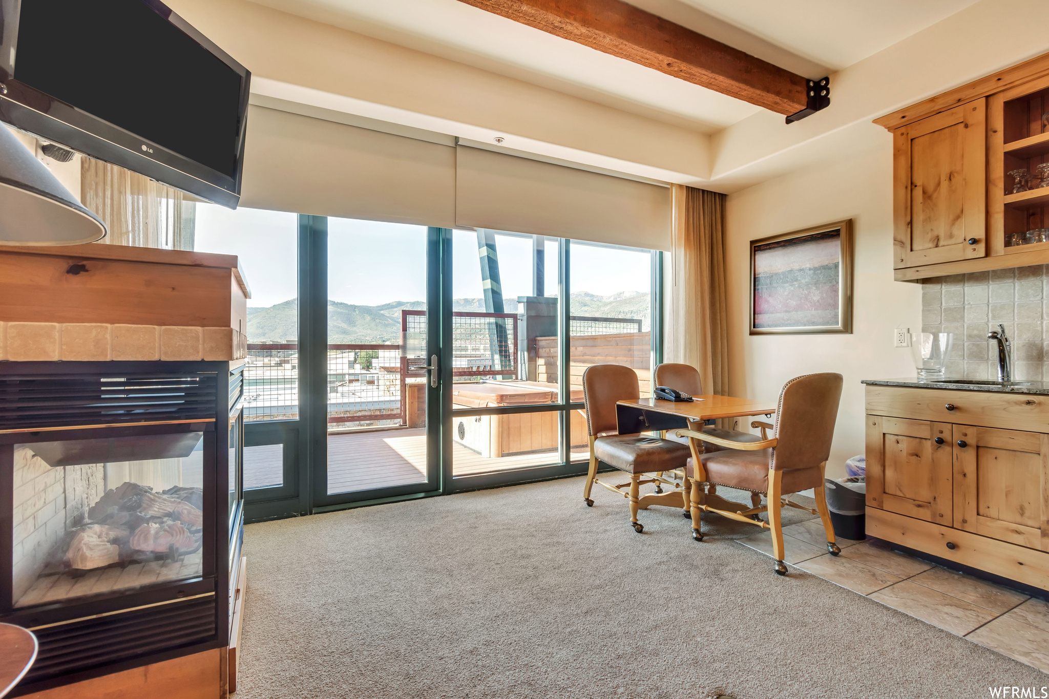 Home office featuring light colored carpet, a fireplace, sink, and beamed ceiling