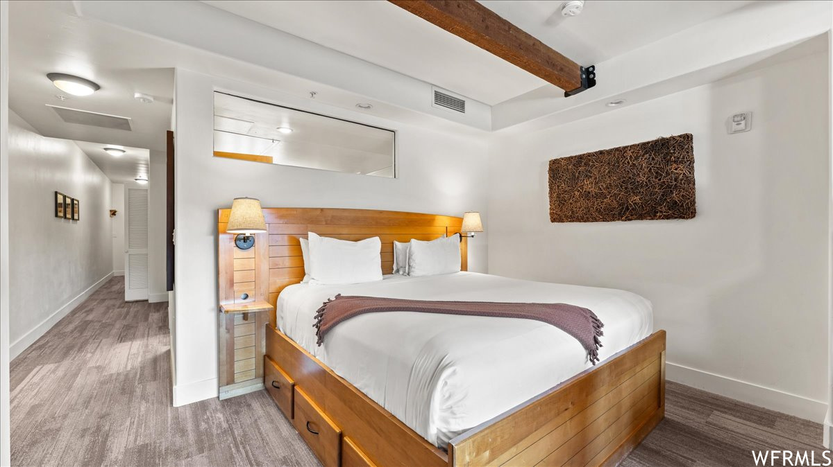 Hardwood floored bedroom featuring beamed ceiling