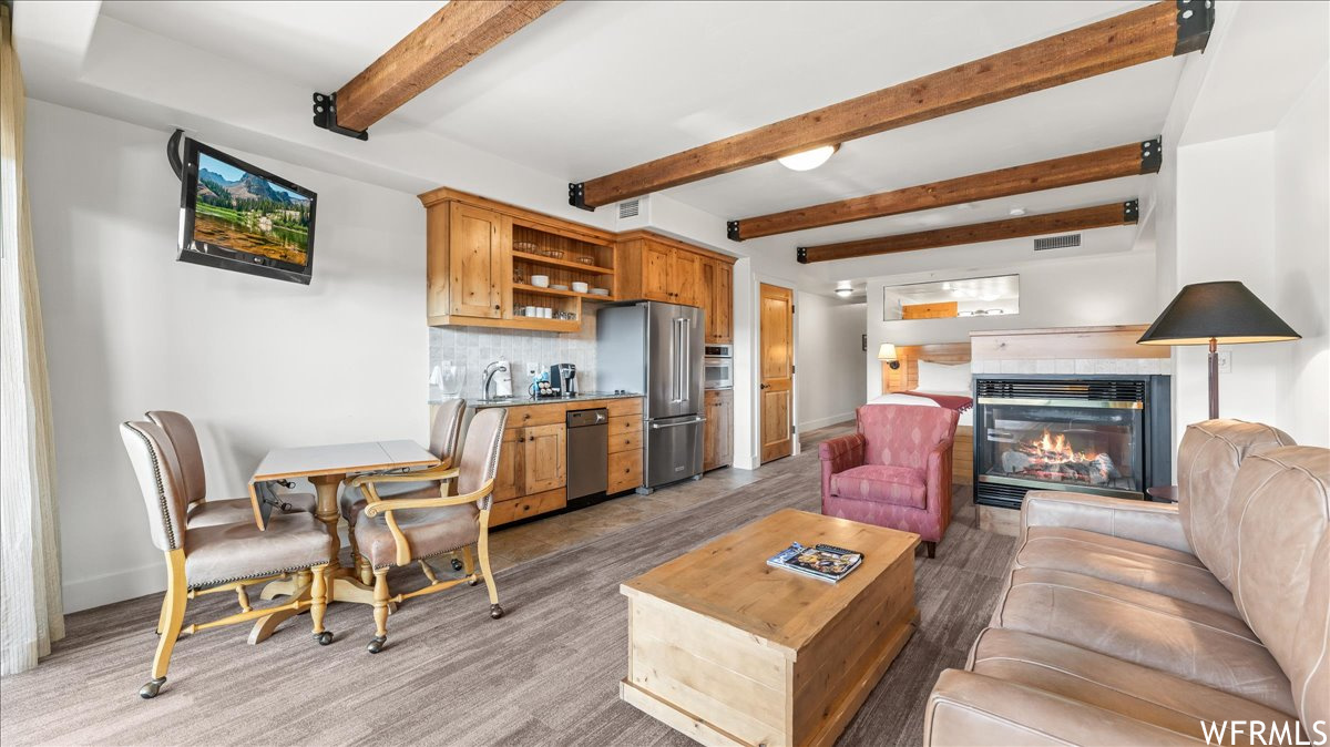 Living room featuring sink, beam ceiling, light hardwood floors, and a fireplace