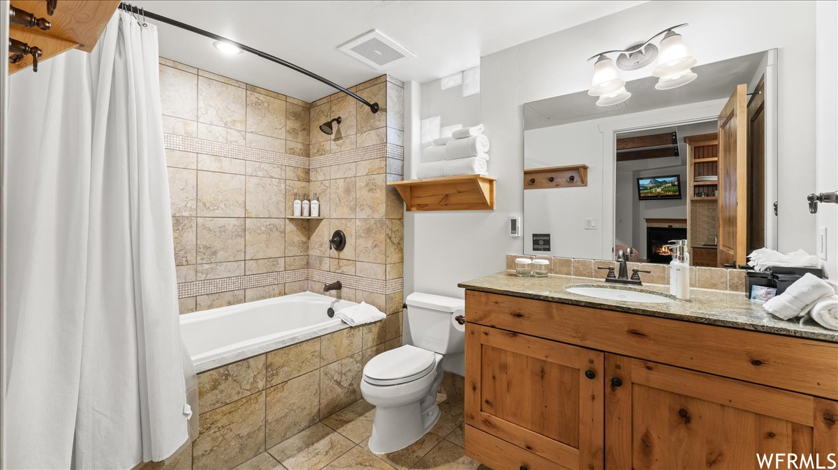 Full bathroom featuring shower / bathtub combination with curtain, vanity, tile flooring, and toilet