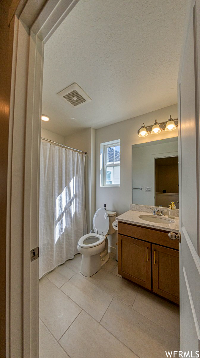 2nd full Bathroom featuring a textured ceiling, vanity, tile floors, and toilet
