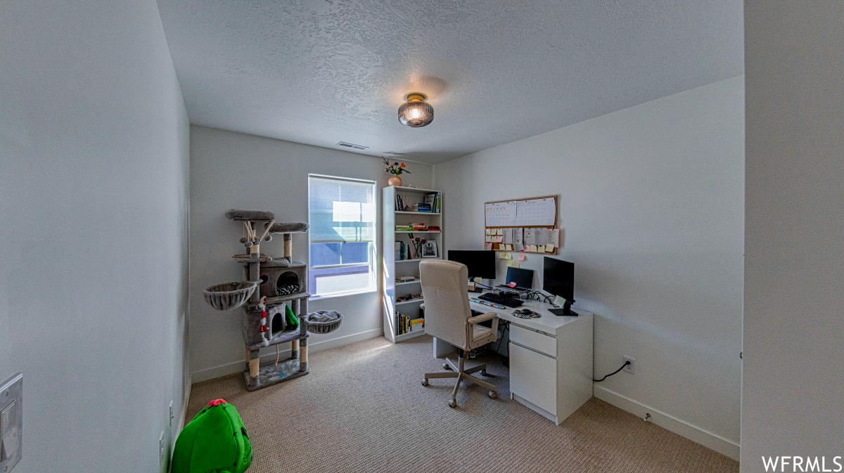 3rd bedroom used as an Office space featuring light colored carpet and a textured ceiling