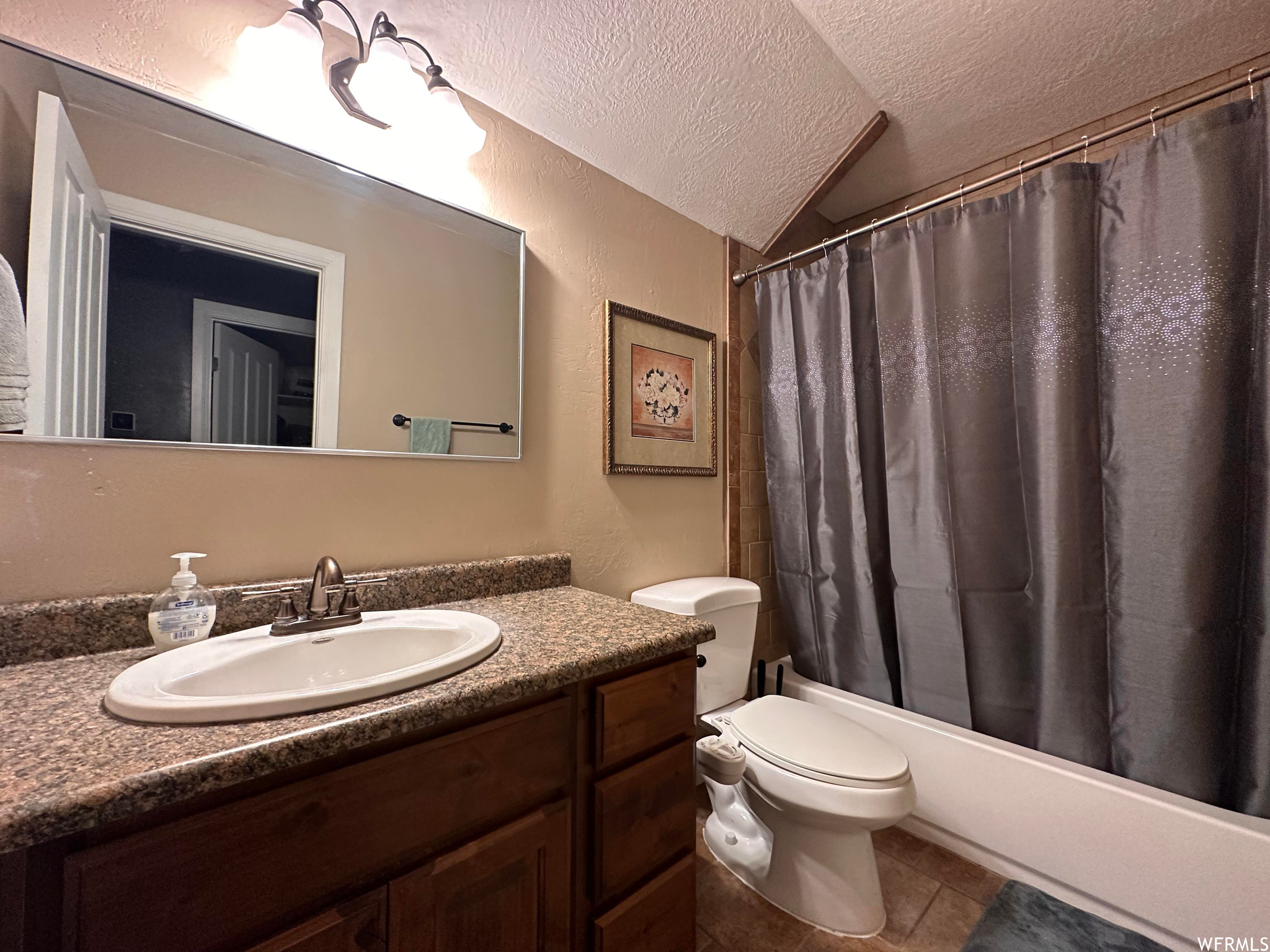 Full bathroom with toilet, a textured ceiling, tile floors, oversized vanity, and shower / tub combo