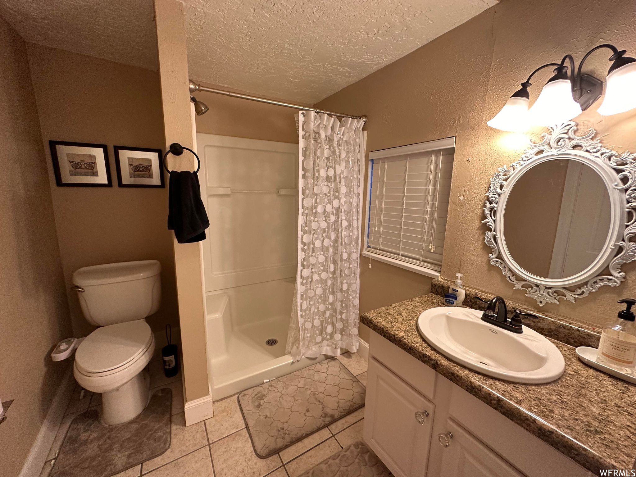 Bathroom featuring toilet, a shower with shower curtain, a textured ceiling, tile floors, and oversized vanity