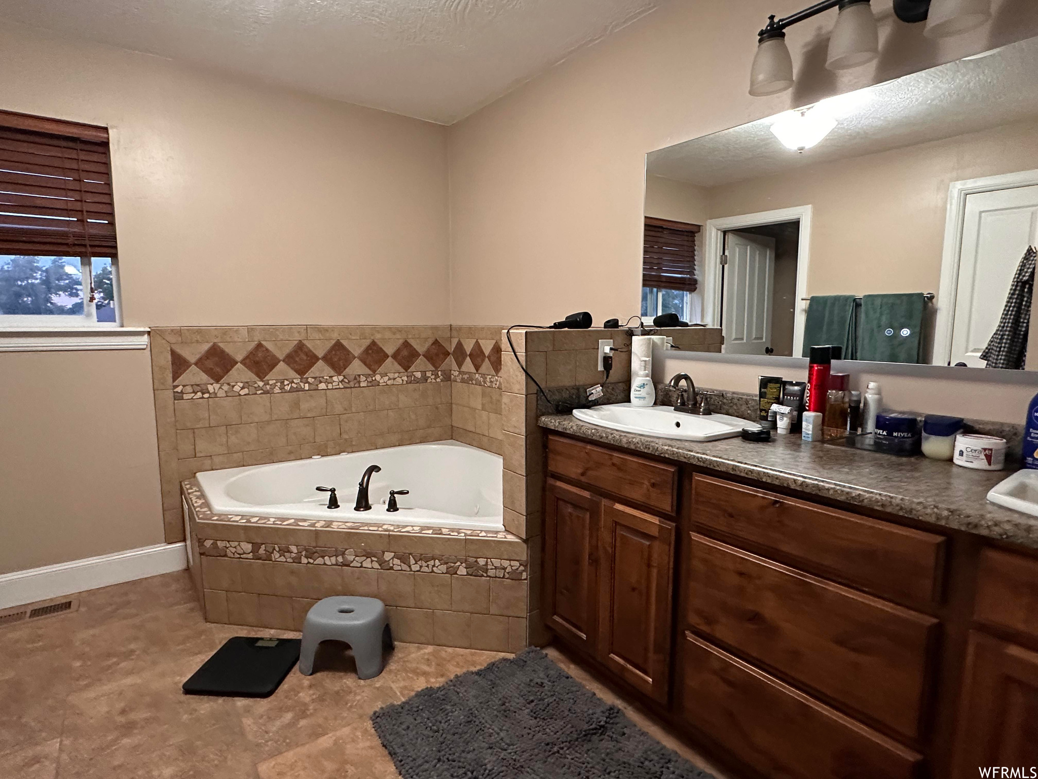 Bathroom featuring tile floors, tiled tub, and vanity with extensive cabinet space