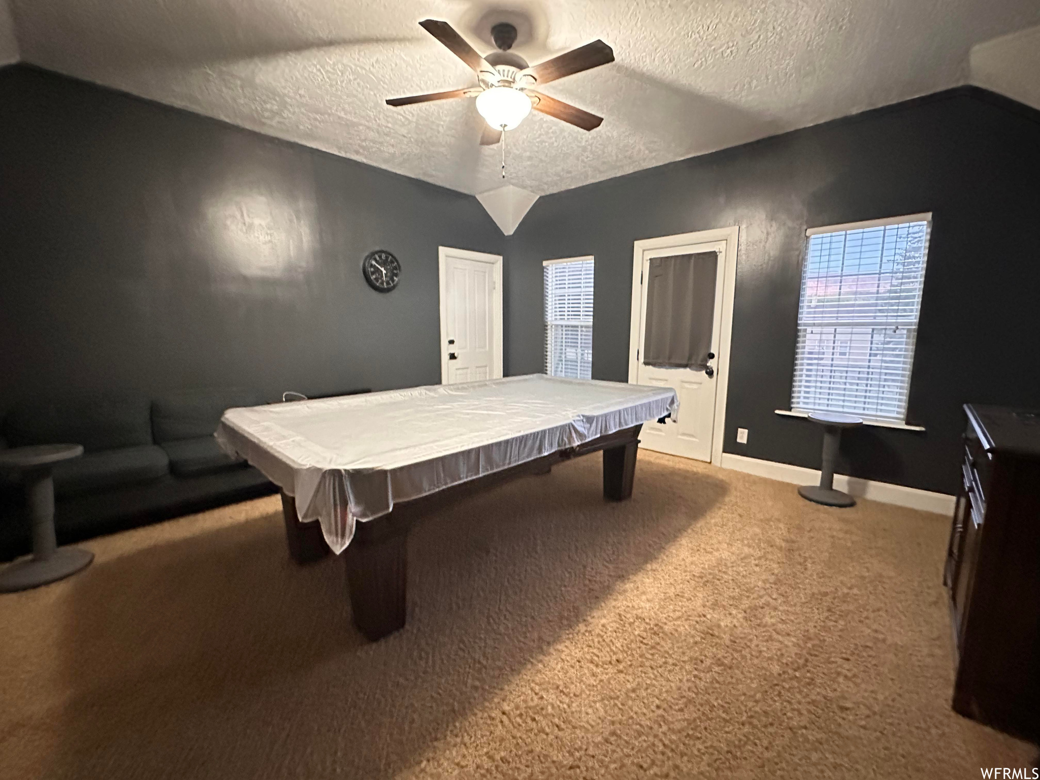 Recreation room featuring a textured ceiling, pool table, carpet, and ceiling fan
