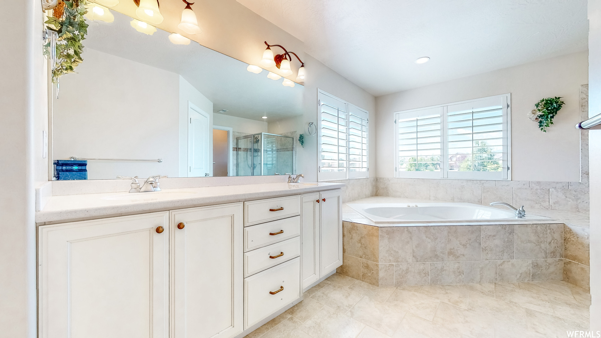 Primary bathroom with vanity with extensive cabinet space, independent shower and bath, tile flooring, and dual sinks