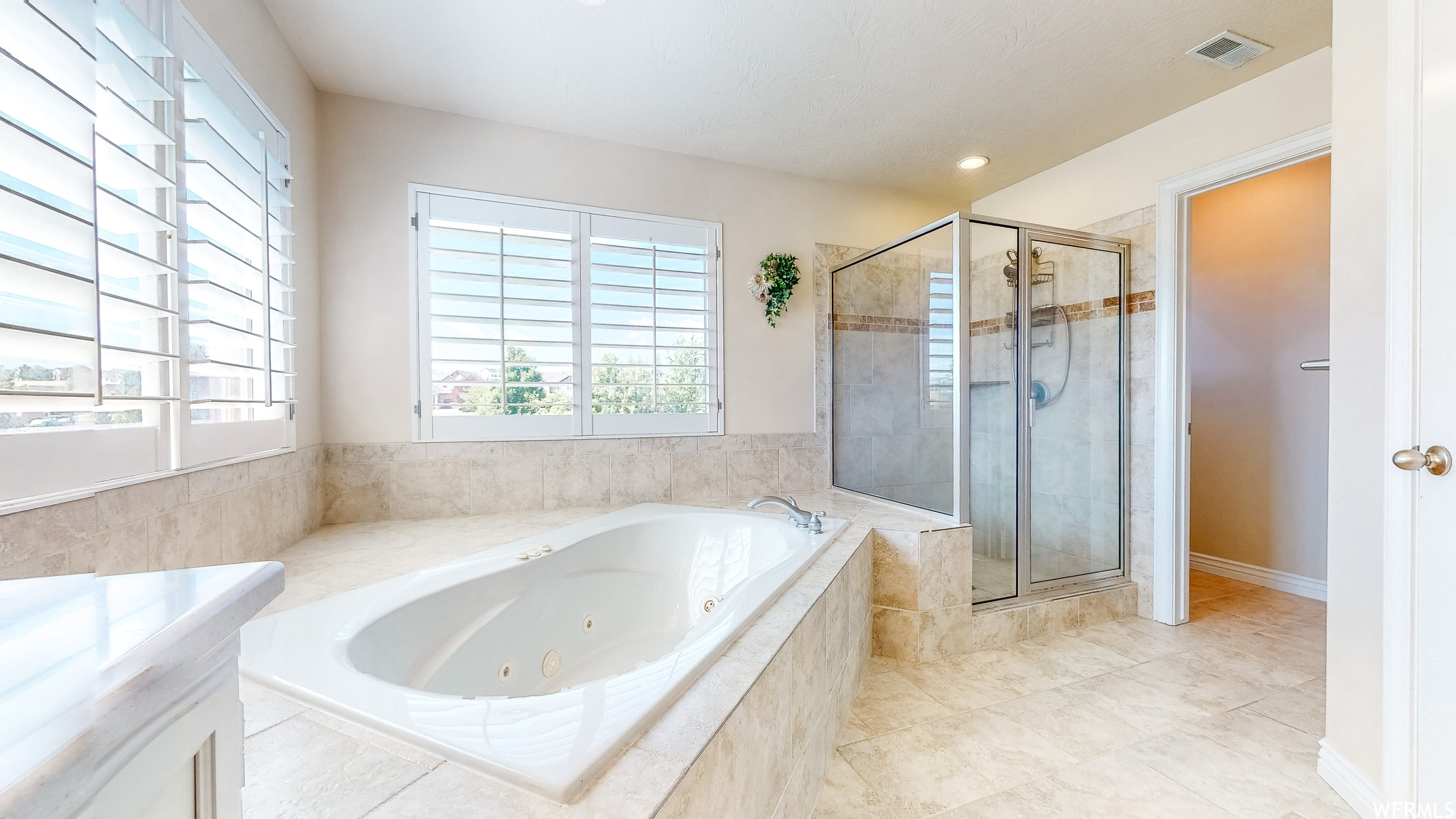 Primary bathroom featuring separate shower and tub and tile floors