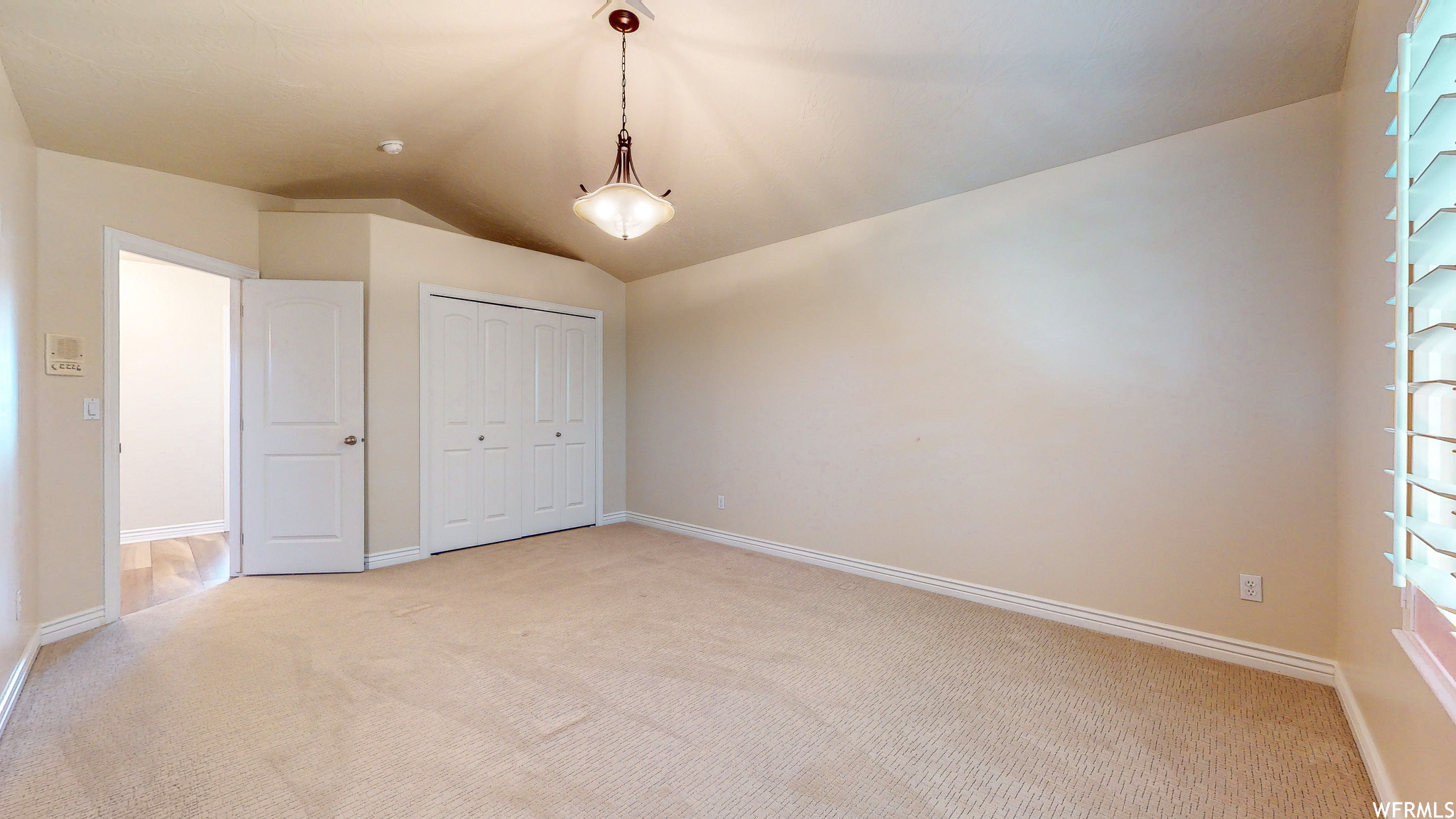 Unfurnished bedroom with lofted ceiling, a closet, and light colored carpet