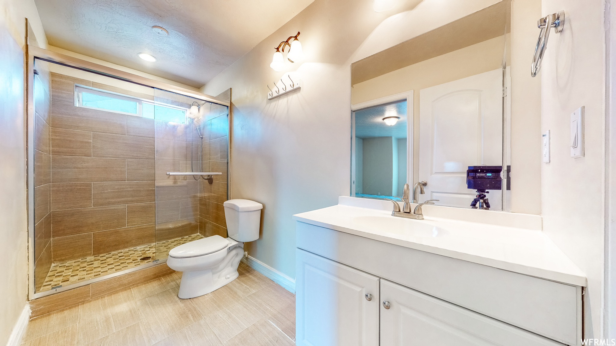 Bathroom featuring tile floors, large vanity, walk in shower, and toilet