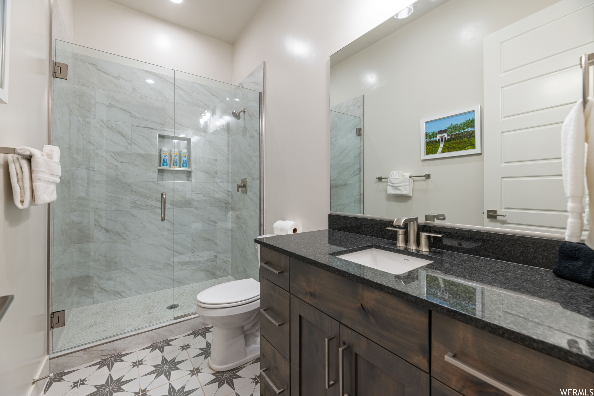 Bathroom with tile floors, an enclosed shower, toilet, and vanity