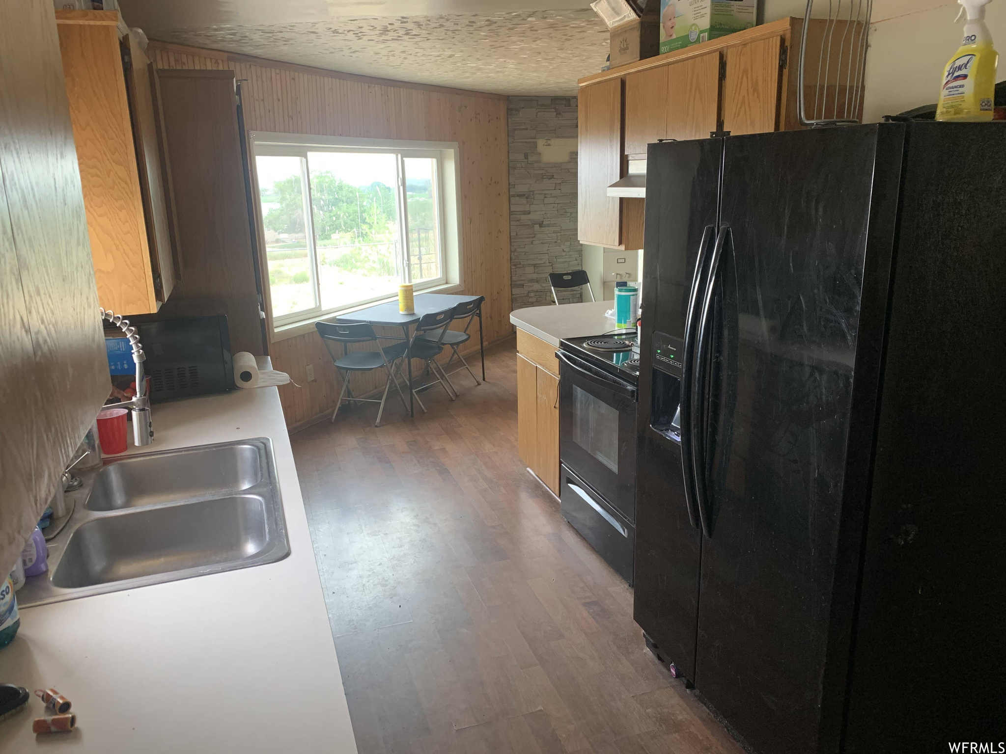 Kitchen with black appliances, a textured ceiling, dark hardwood flooring, and sink