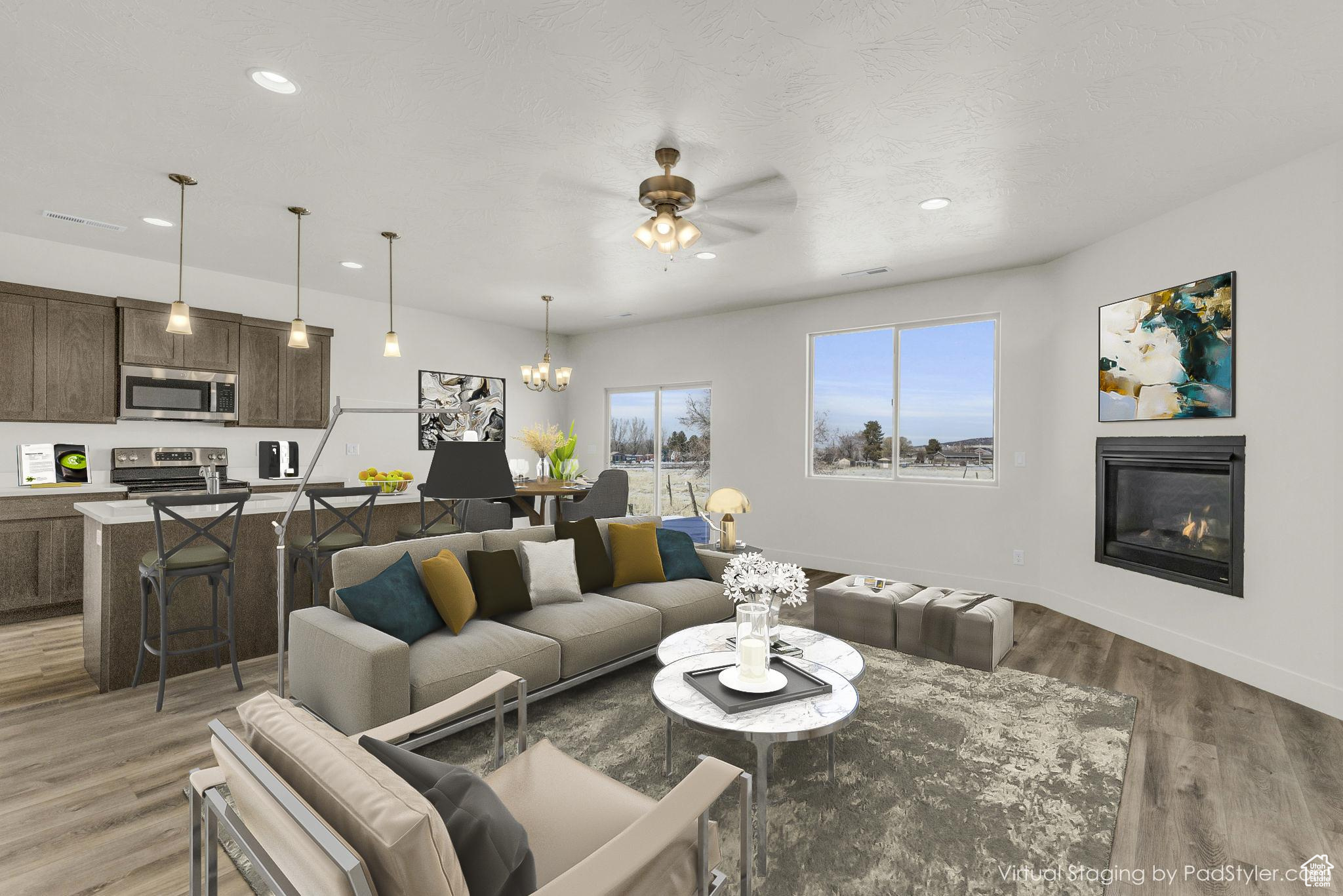 Living room with ceiling fan with notable chandelier and light hardwood / wood-style floors