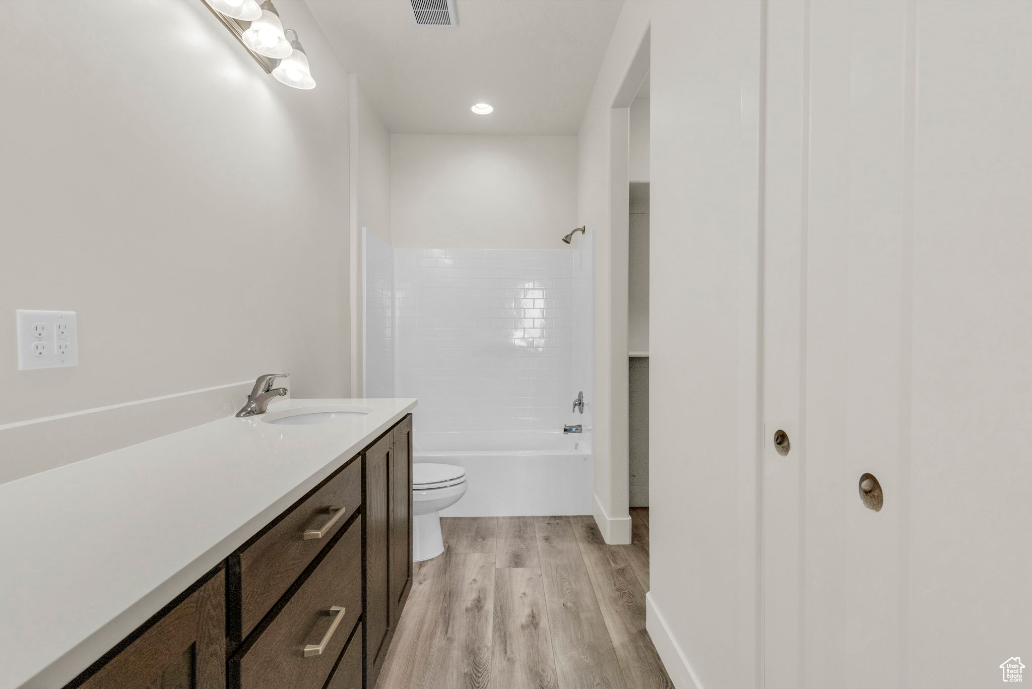 Full bathroom with hardwood / wood-style flooring,  shower combination, vanity, and toilet