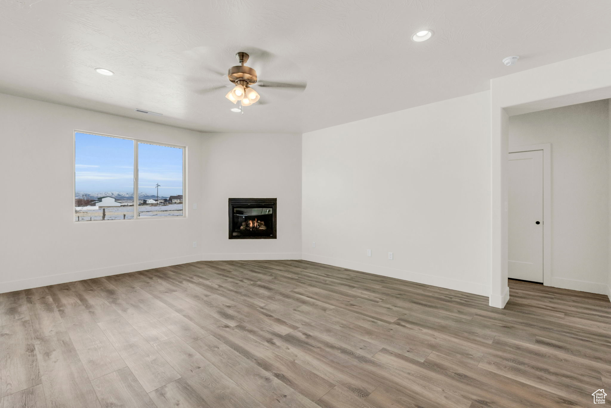 Unfurnished living room featuring ceiling fan and light wood-type flooring