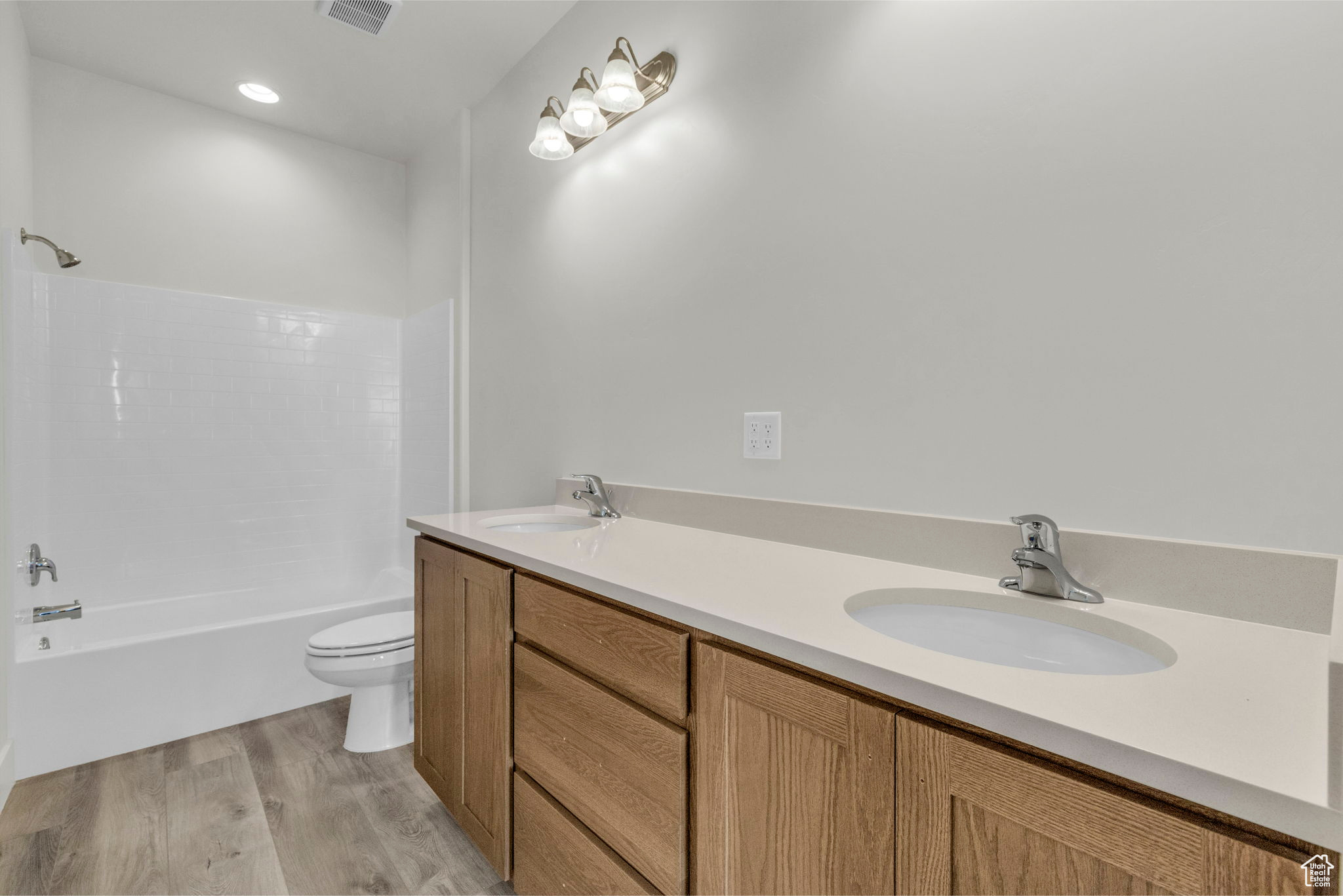 Full bathroom featuring shower / washtub combination, toilet, hardwood / wood-style floors, and dual bowl vanity