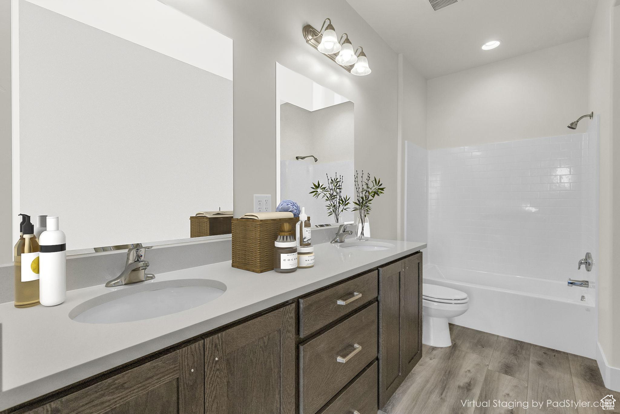 Full bathroom with shower / washtub combination, hardwood / wood-style flooring, vanity, and toilet