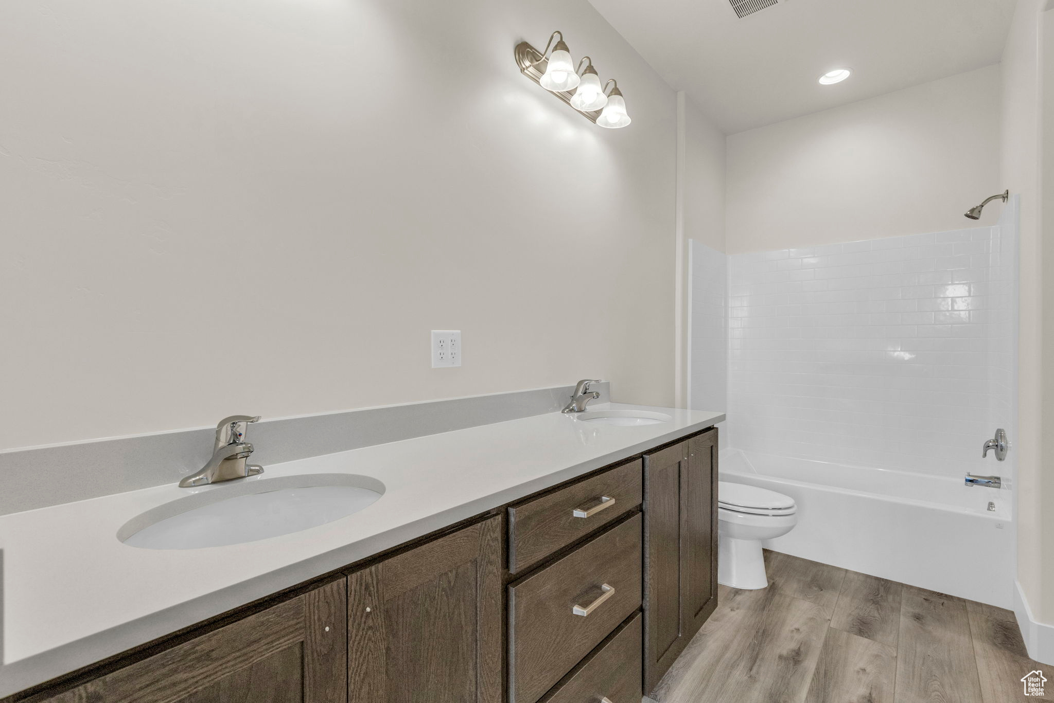 Full bathroom with toilet, double vanity, shower / bathtub combination, and hardwood / wood-style flooring