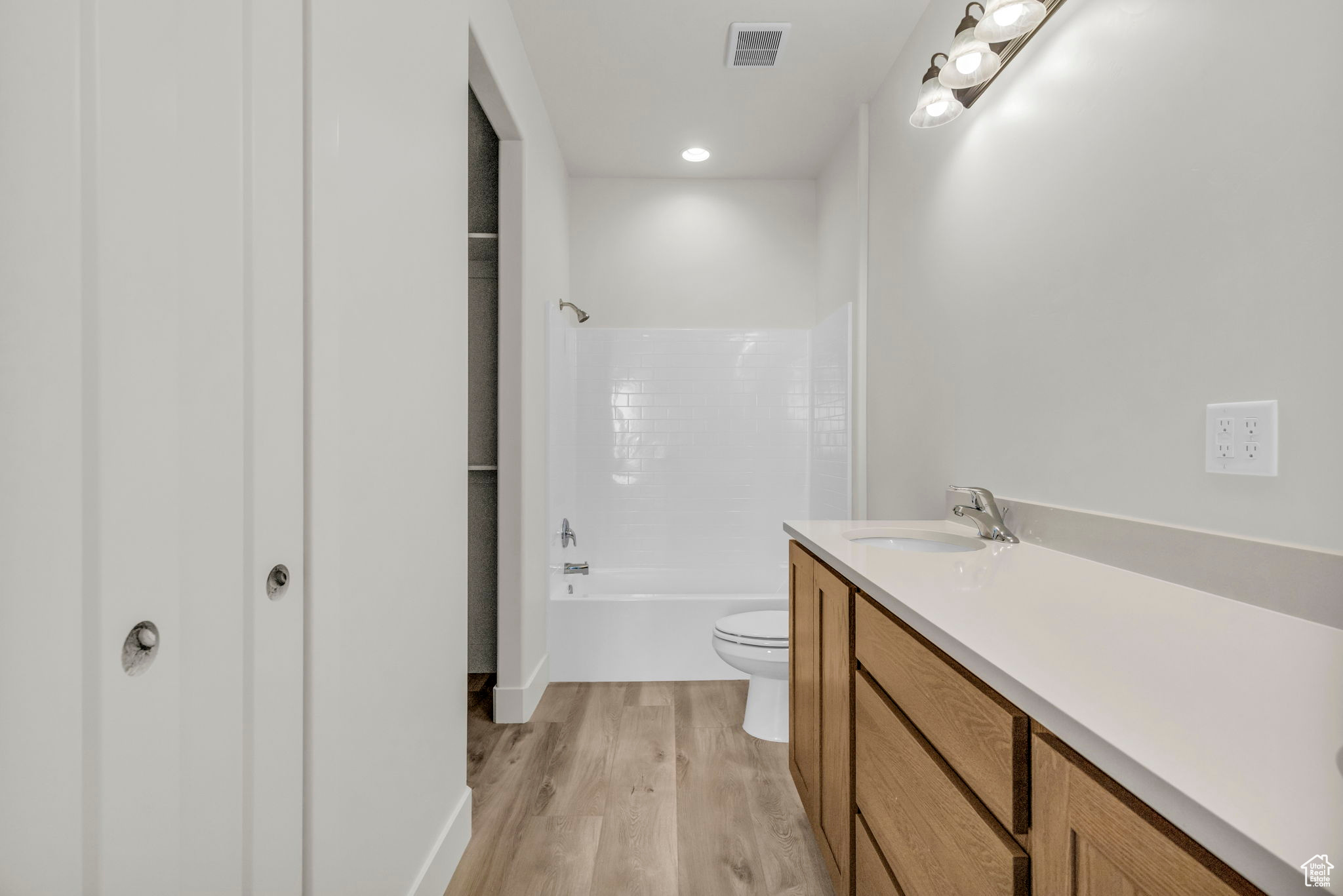 Full bathroom with shower / bathtub combination, hardwood / wood-style flooring, vanity, and toilet