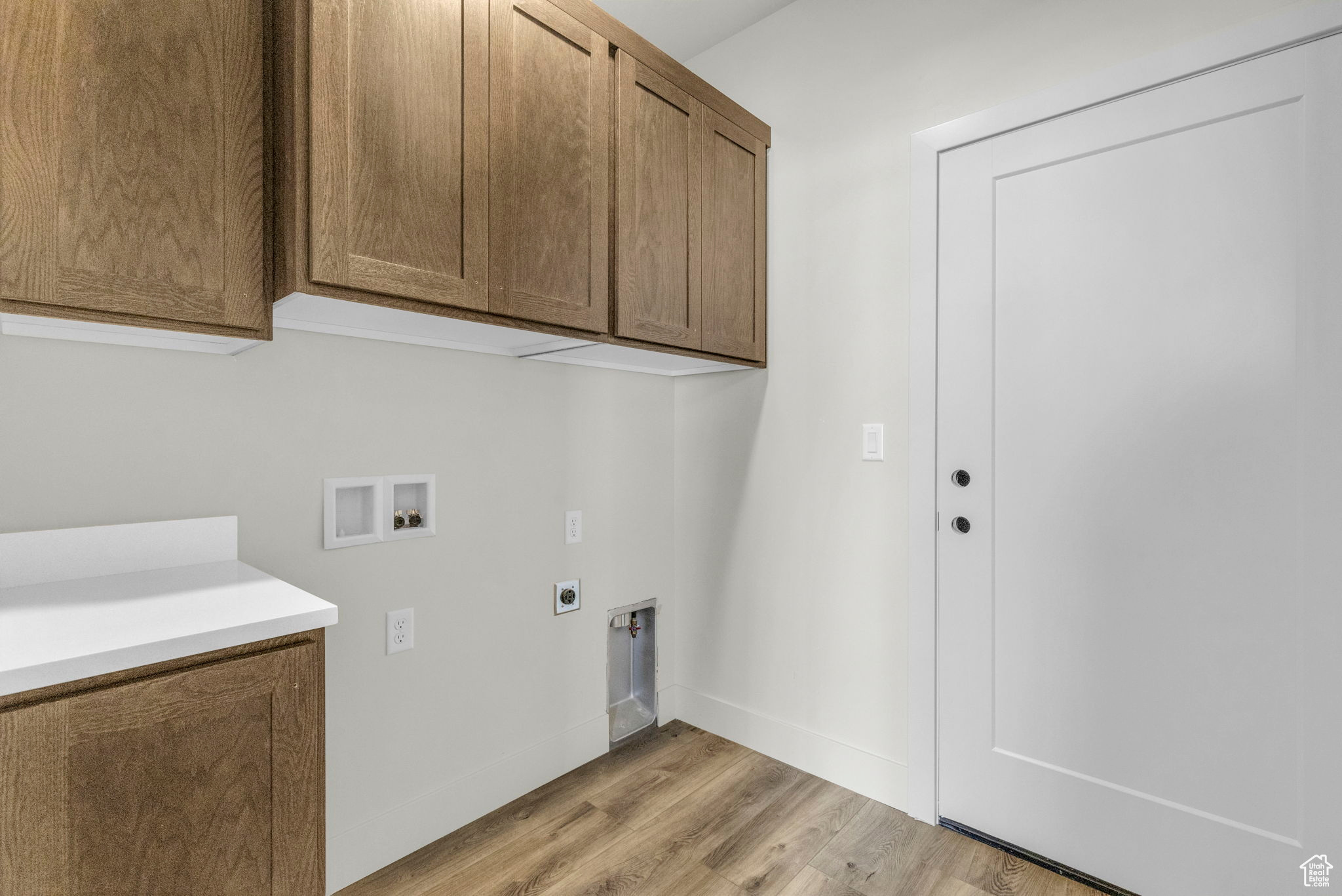 Laundry room with cabinets, hookup for a washing machine, hookup for an electric dryer, and light wood-type flooring
