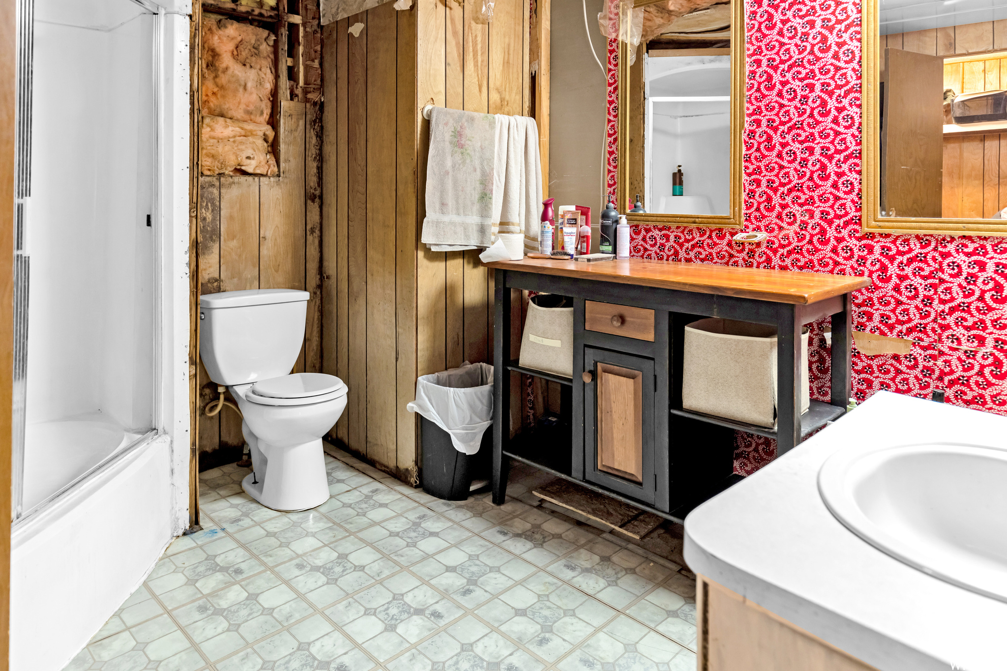 Full bathroom featuring tile flooring, vanity, toilet, wooden walls, and shower / bath combo