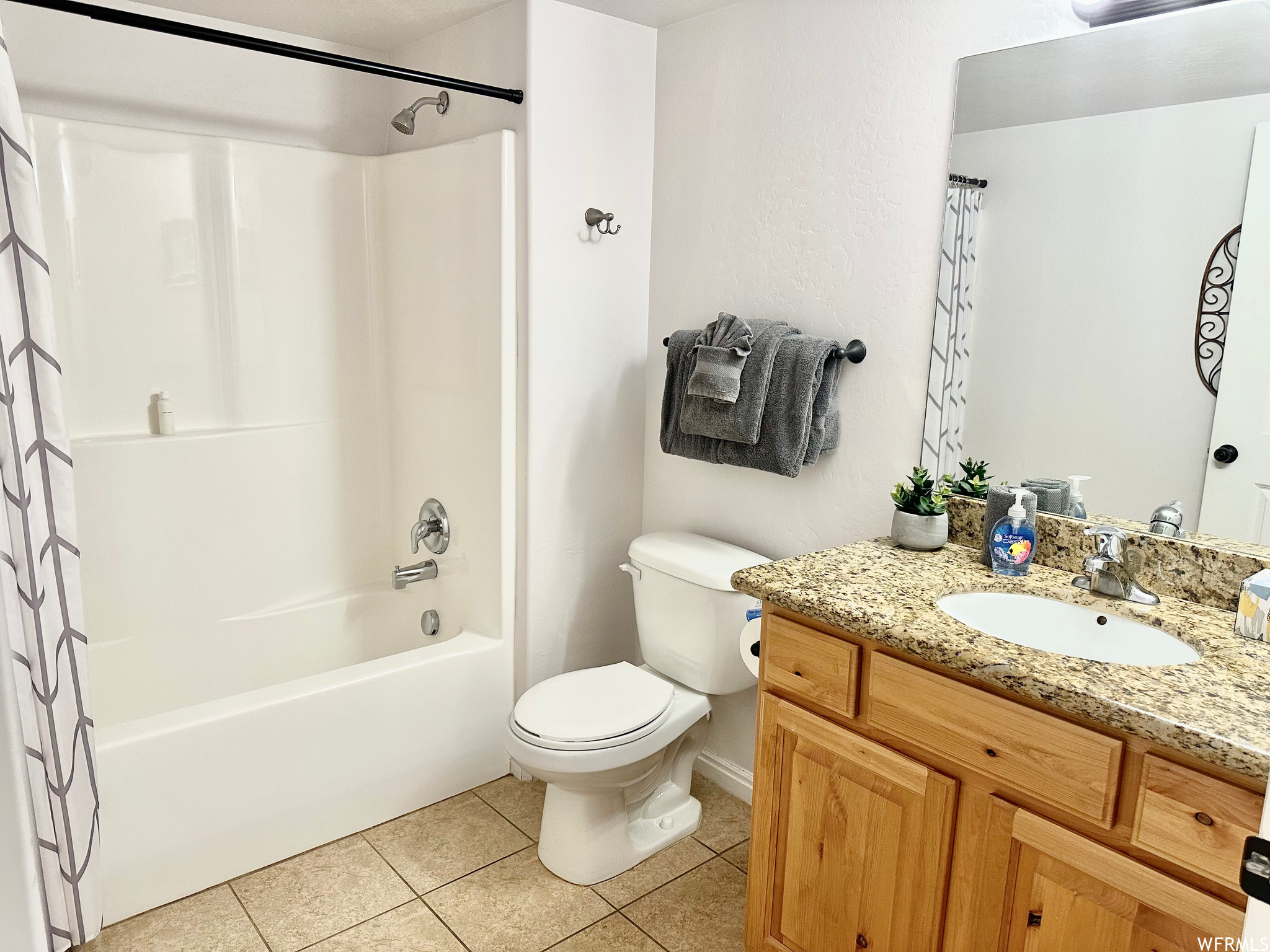Full bathroom with tile flooring, toilet, shower / tub combo with curtain, and vanity