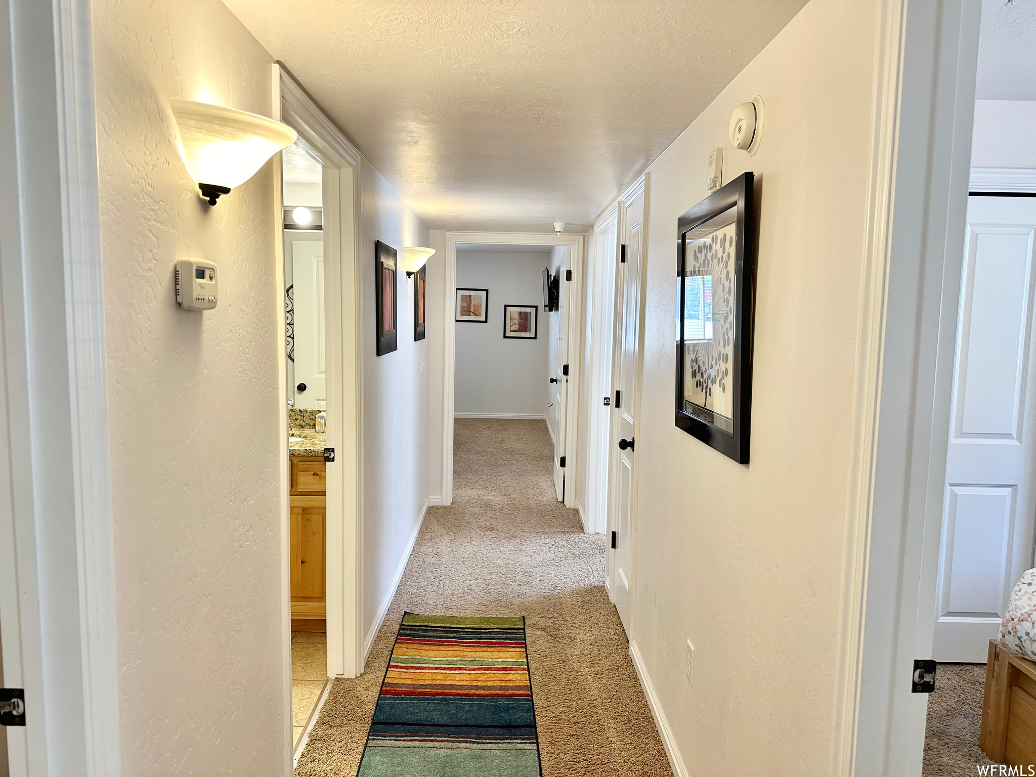 Corridor with light colored carpet and a textured ceiling
