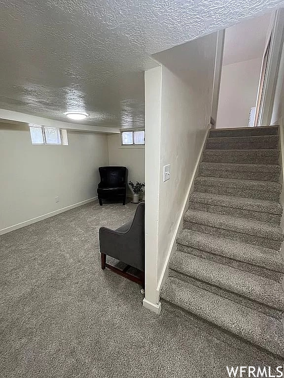Stairway with carpet, a healthy amount of sunlight, and a textured ceiling