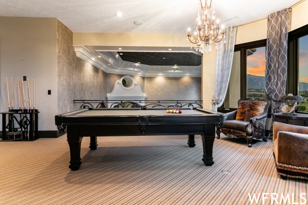 Game room with a tray ceiling, an inviting chandelier, pool table, and carpet flooring