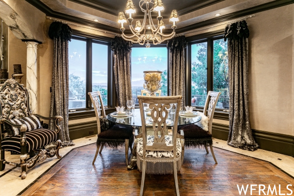 Dining area featuring a healthy amount of sunlight, dark hardwood floors, and an inviting chandelier