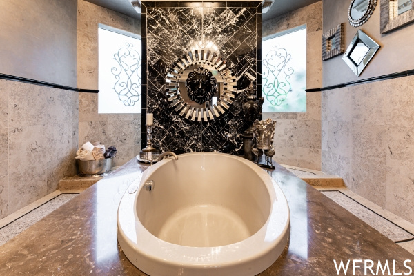 Bathroom featuring plenty of natural light, tile walls, and a bathtub