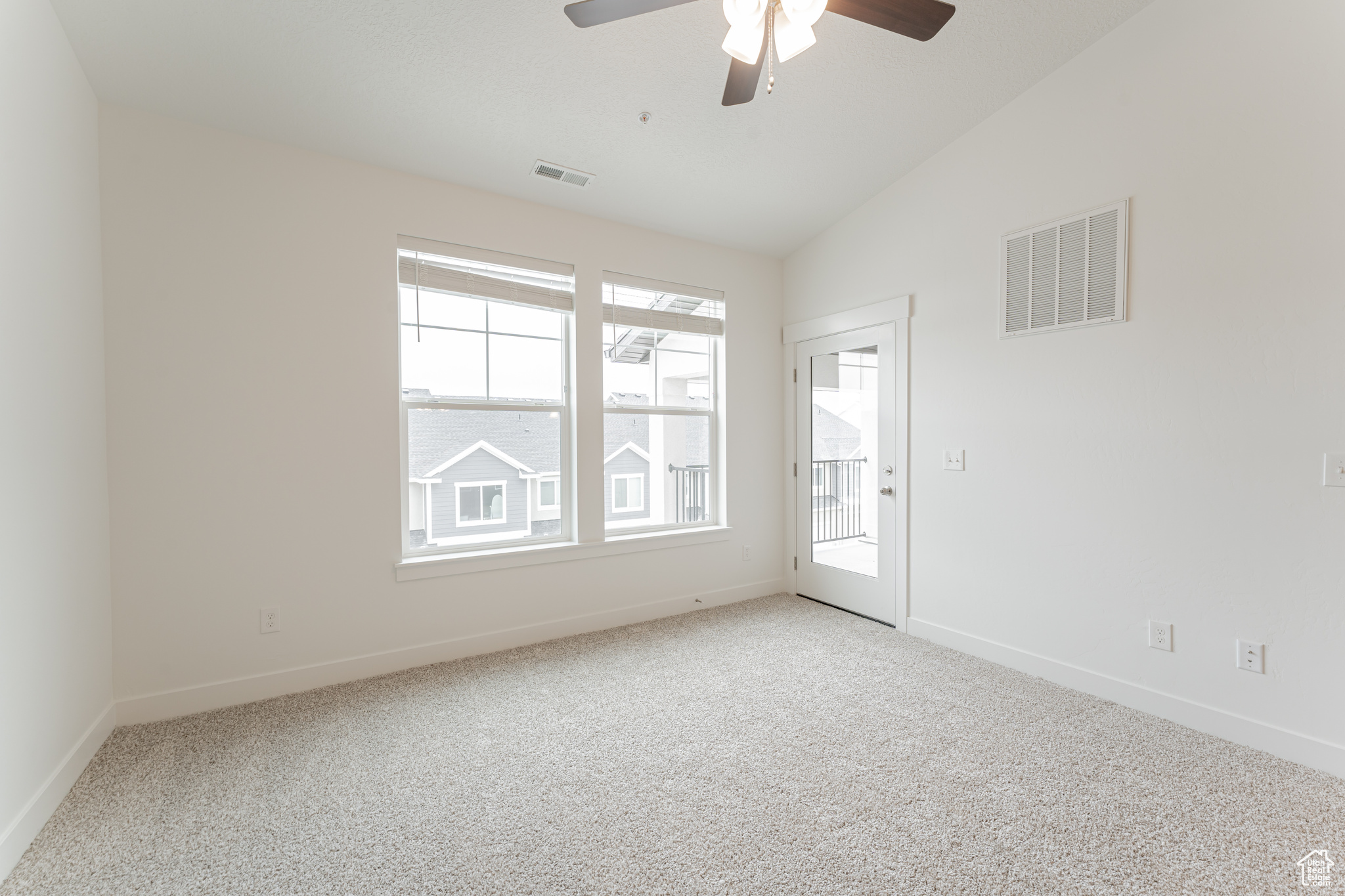 Spare room featuring light carpet, ceiling fan, and vaulted ceiling