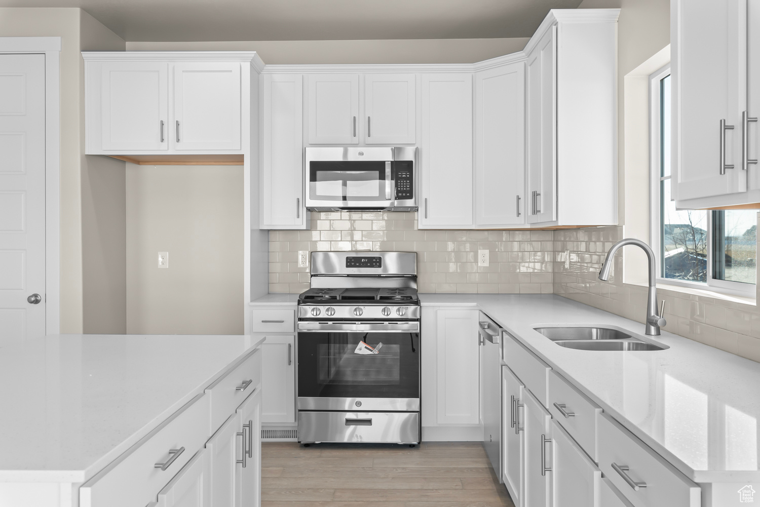 Kitchen with white cabinets, sink, light wood-type flooring, and appliances with stainless steel finishes