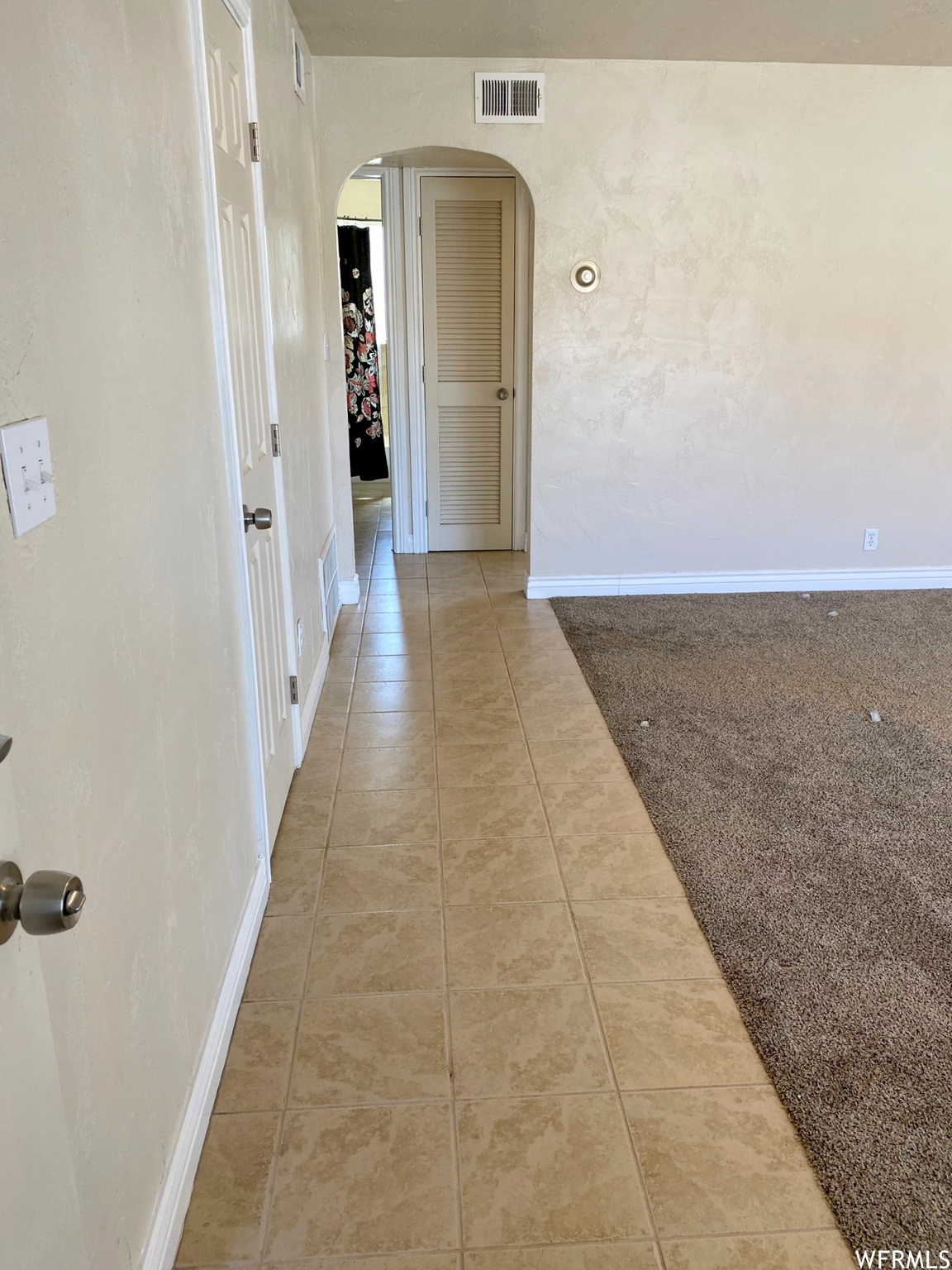 Corridor featuring tile walkway and carpet in living room