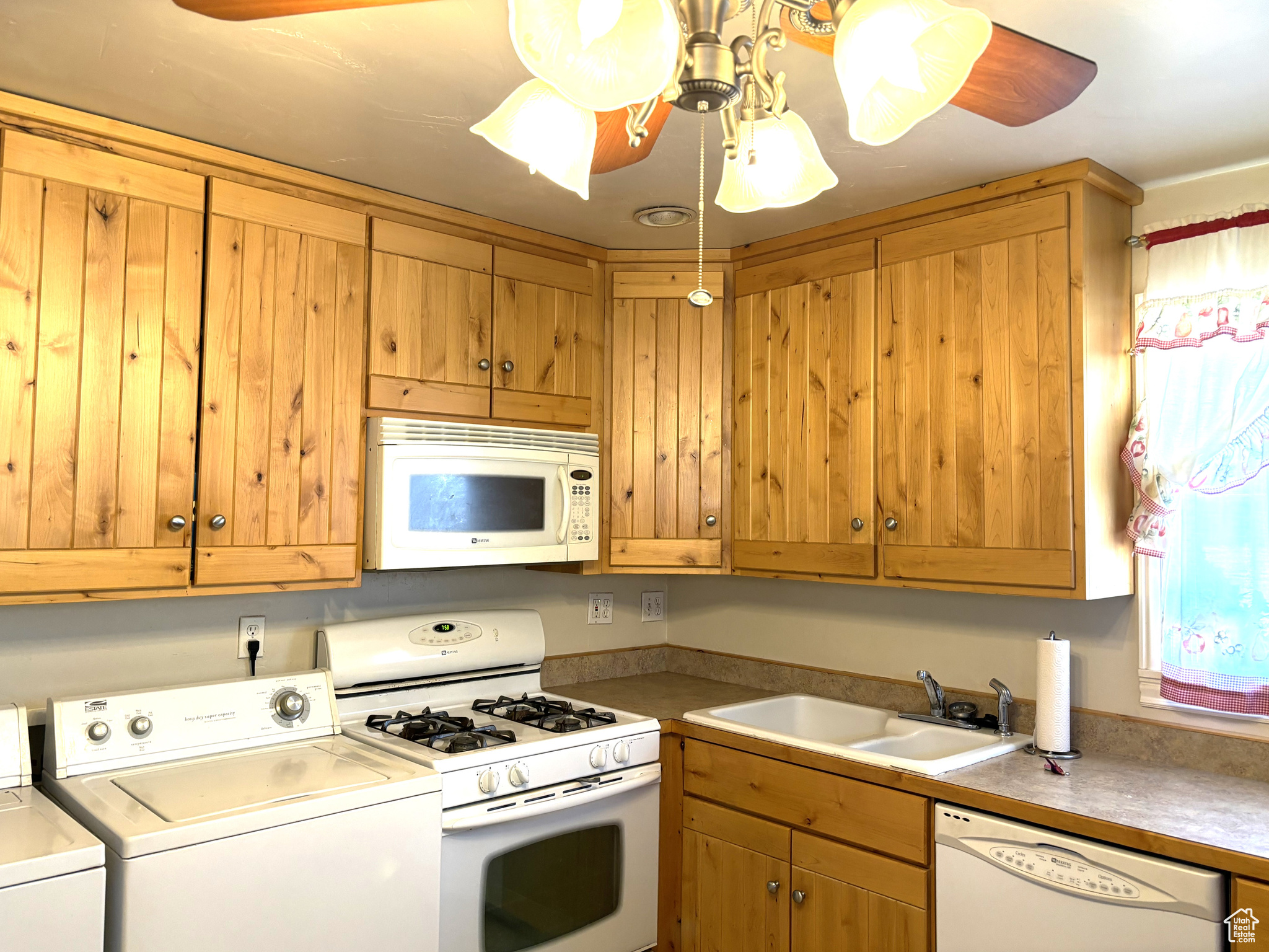 Kitchen with sink, white appliances, independent washer and dryer, and ceiling fan