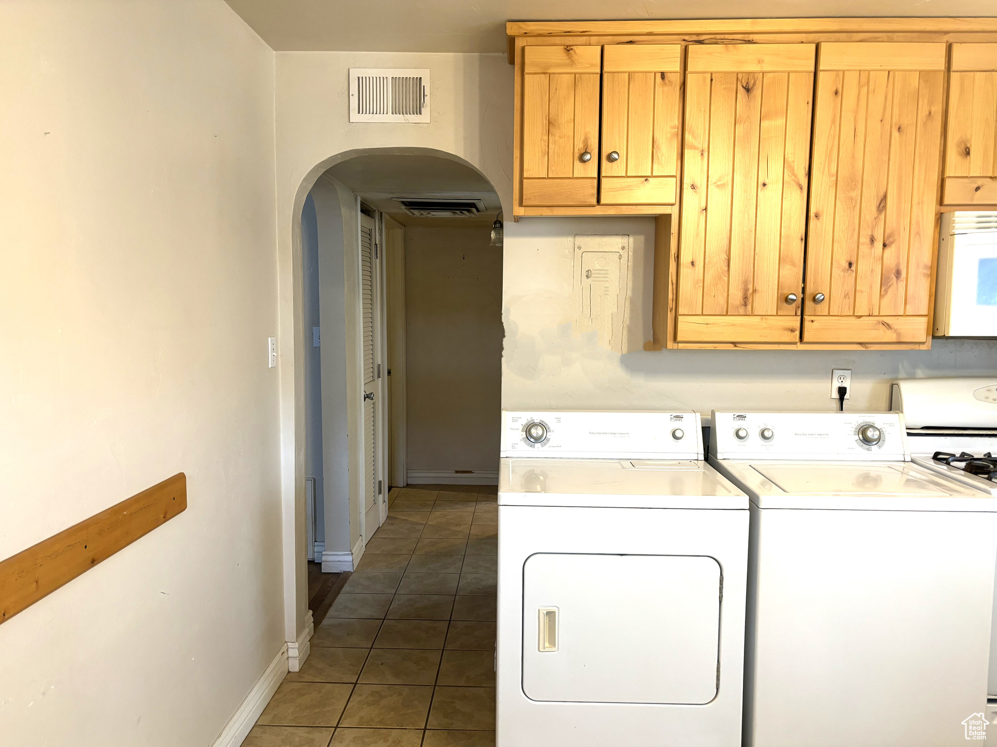 Clothes washing area with dark tile floors and washer and dryer in the kitchen.