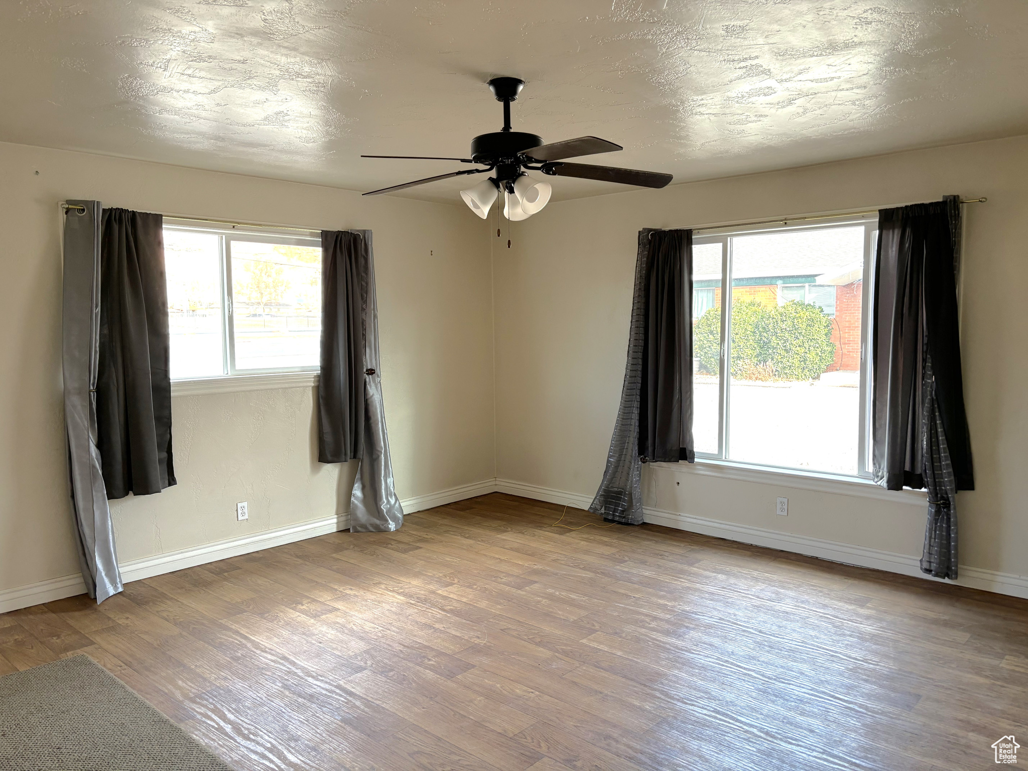 Empty room with ceiling fan, light hardwood / wood-style flooring, and a healthy amount of sunlight