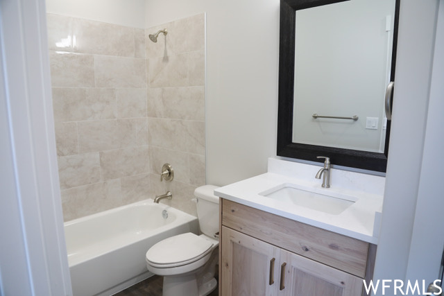 Full bathroom with tiled shower / bath combo, vanity, and toilet