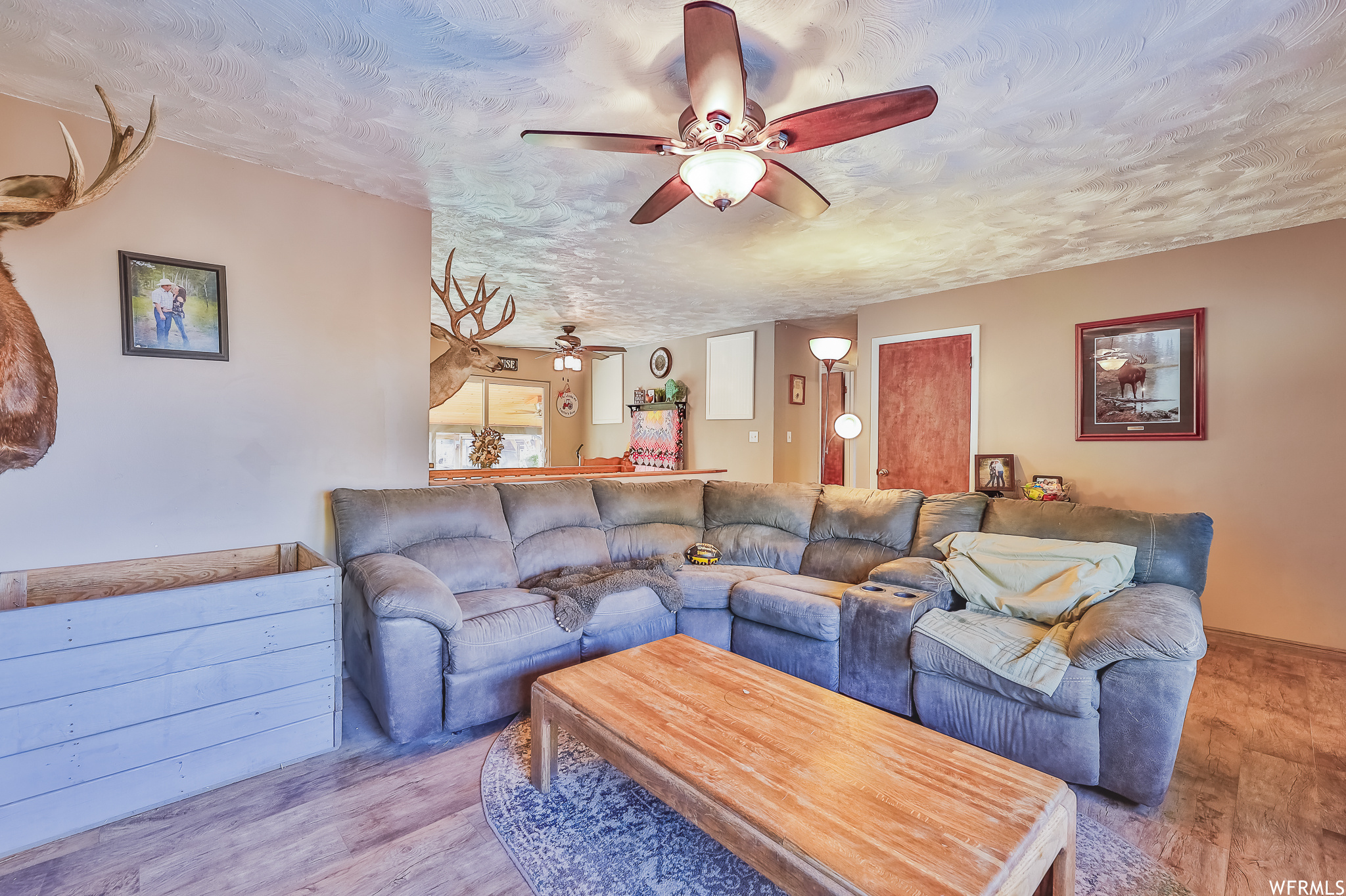 Living room featuring ceiling fan, light hardwood / wood-style flooring, and a textured ceiling