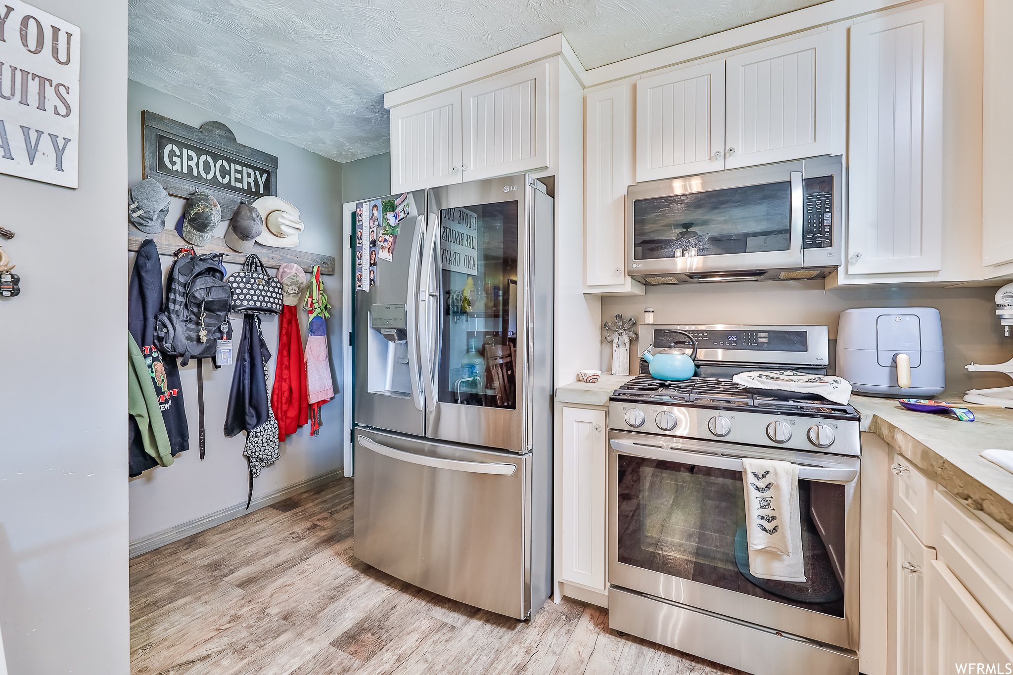Kitchen featuring stainless steel appliances, white cabinets, and light hardwood / wood-style flooring