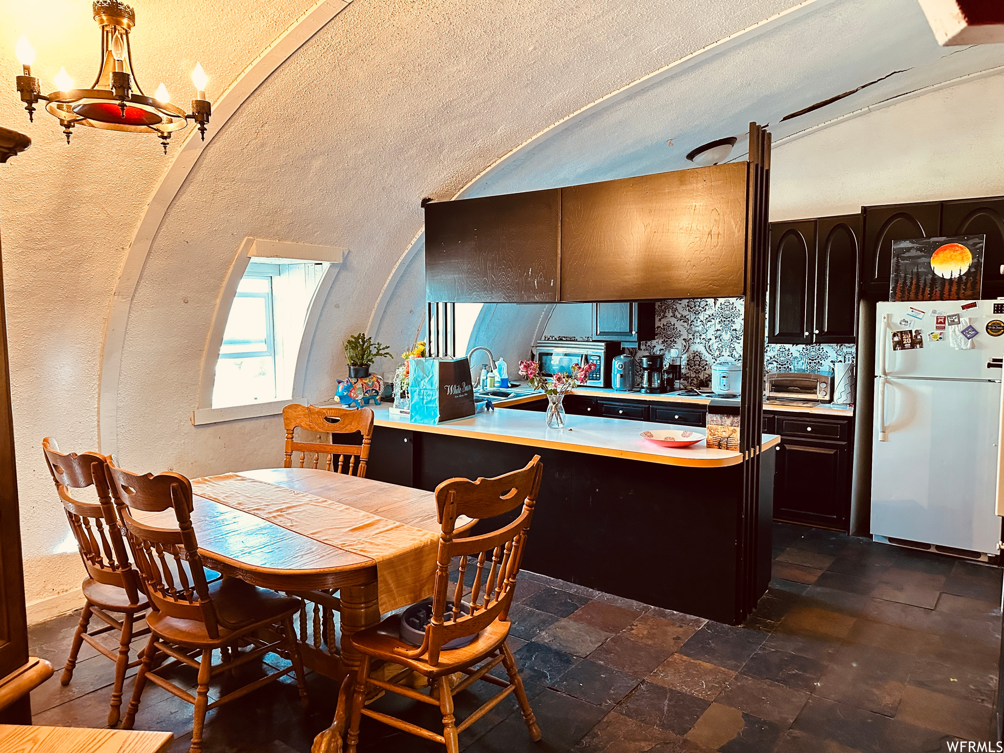 Kitchen with tasteful backsplash, white fridge, a chandelier, dark brown cabinetry, and dark tile floors