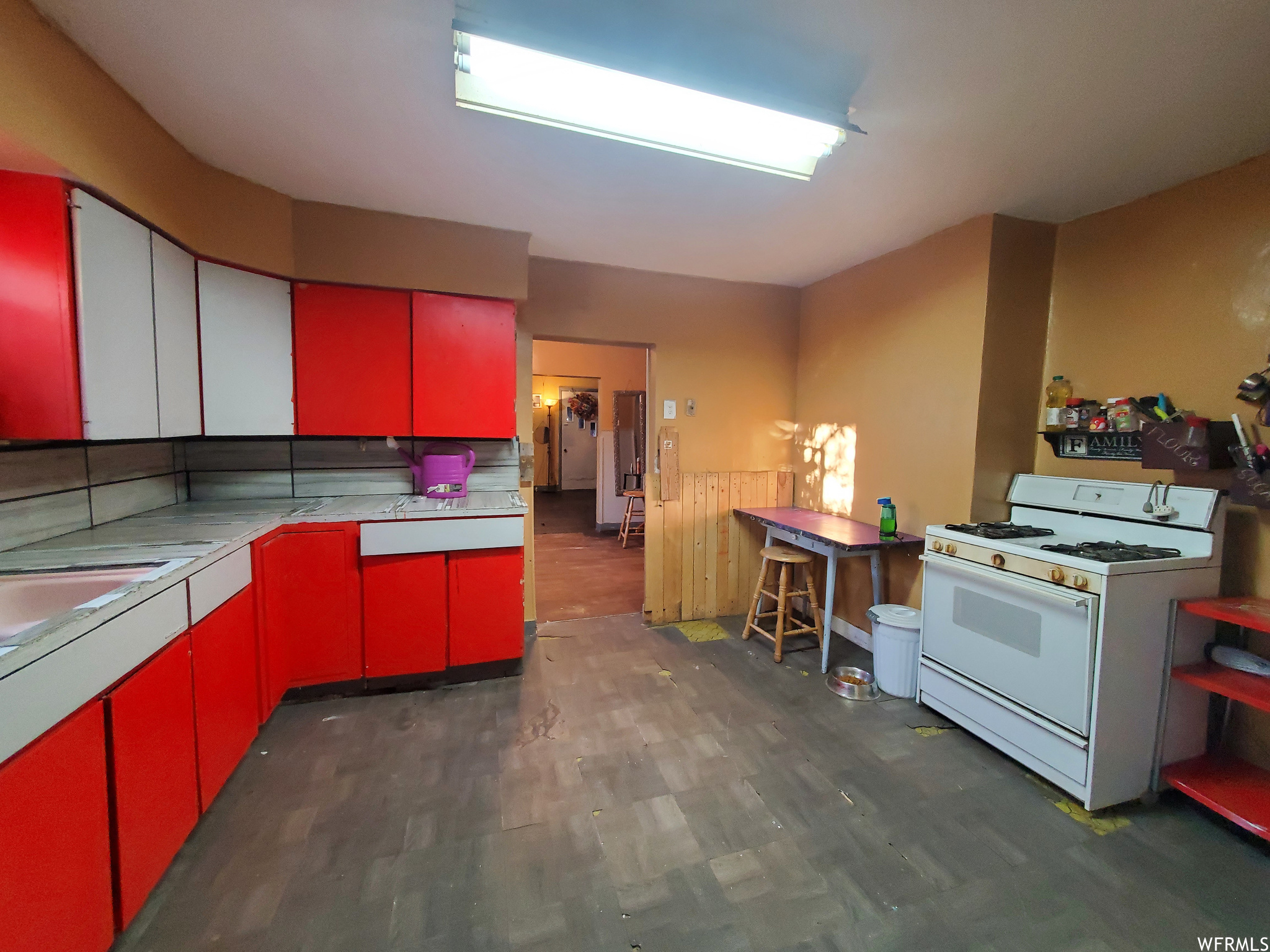 Kitchen with dark hardwood / wood-style flooring, tile countertops, and white gas stove