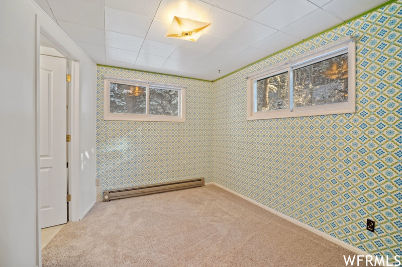 Empty room with light carpet and a baseboard radiator