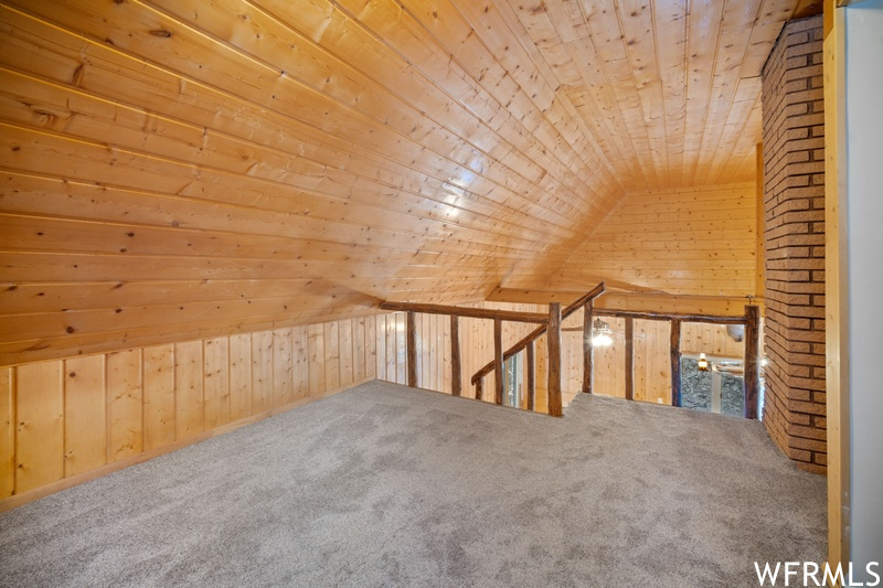 Bonus room featuring wooden walls, lofted ceiling, brick wall, and wooden ceiling