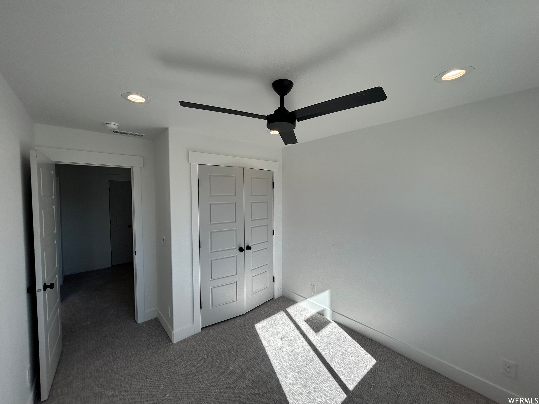 Unfurnished bedroom featuring ceiling fan, dark carpet, and a closet